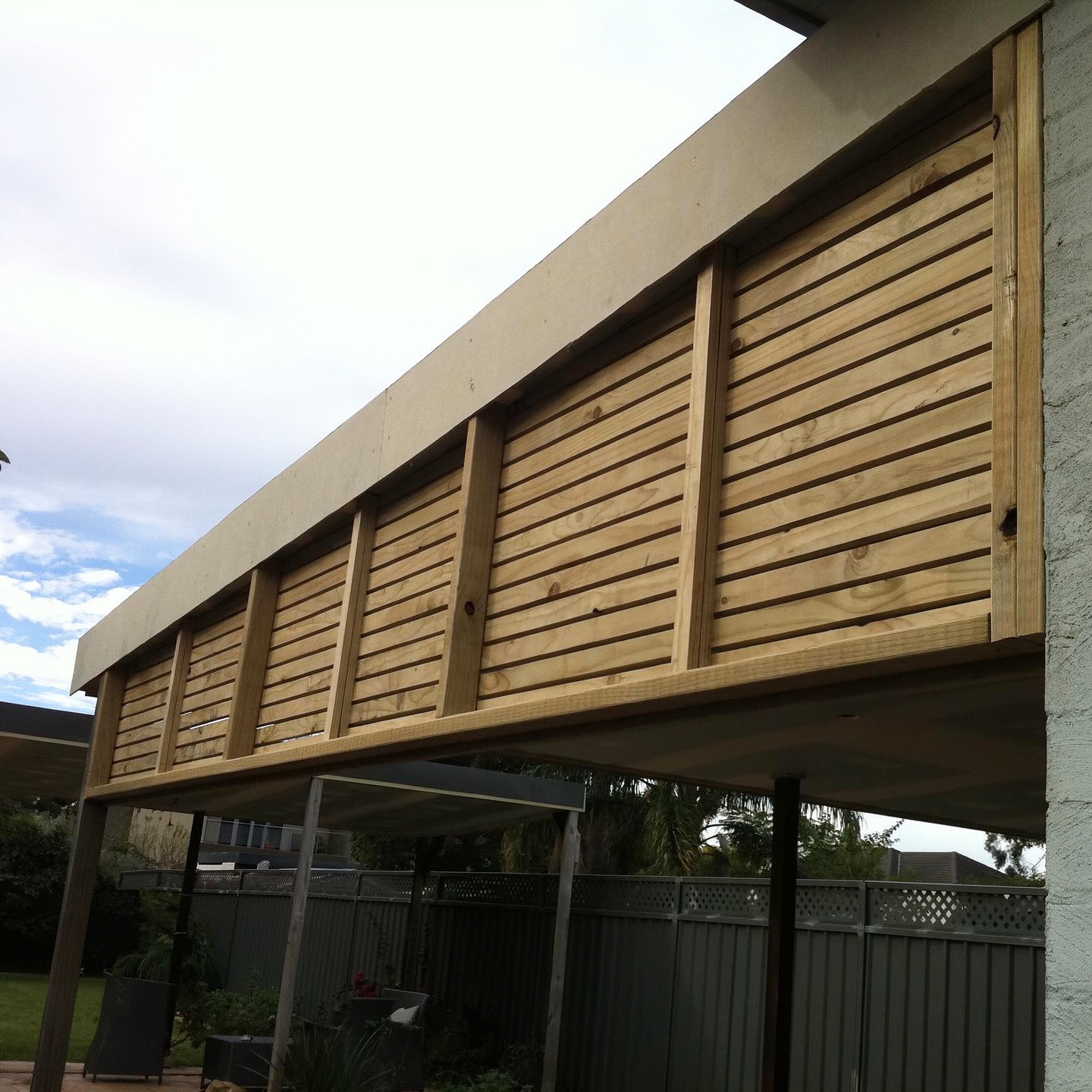 Horizontal timber slat privacy screen fixed under an outdoor roofline