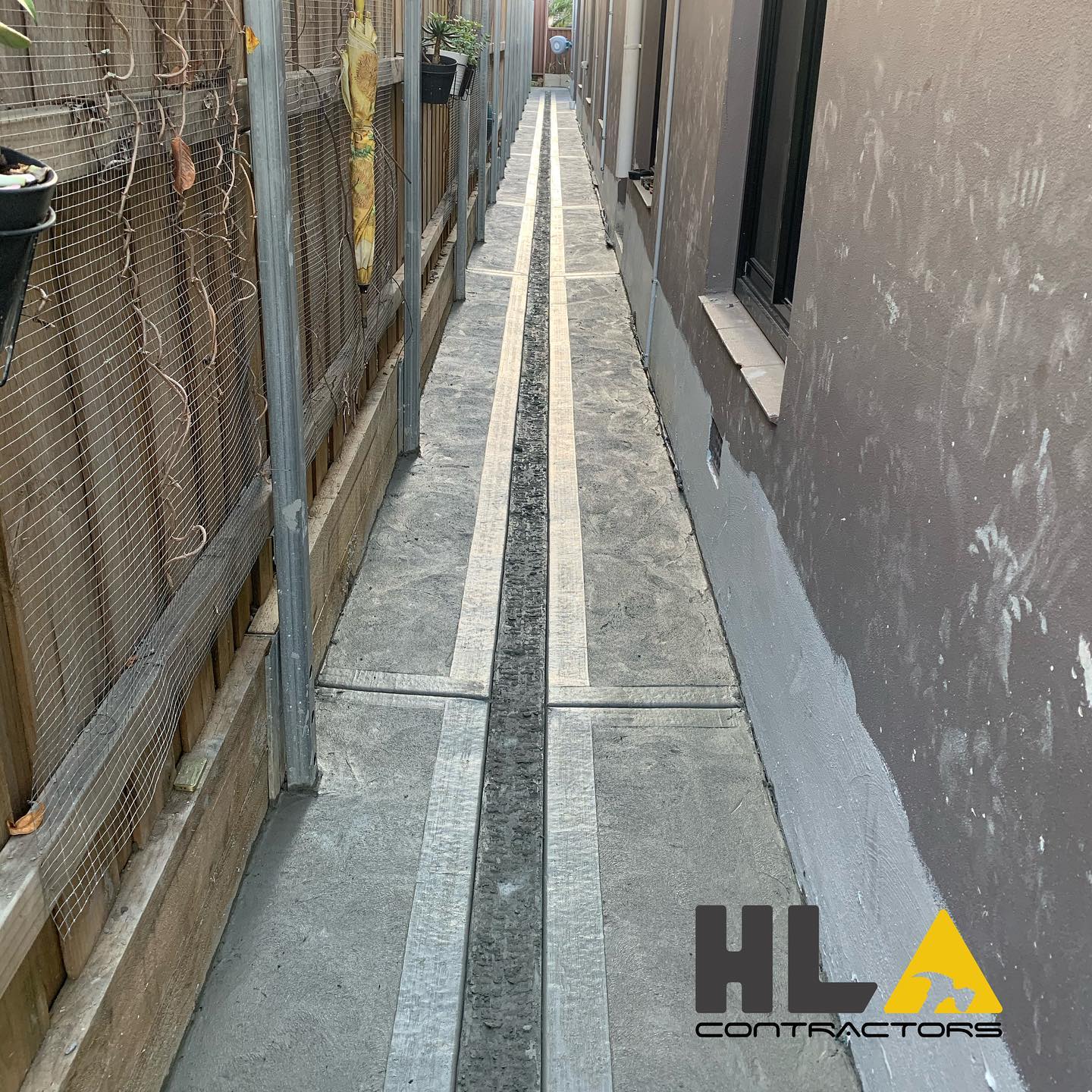 Narrow concrete access path with straight layout, defined edges, and central drainage strip