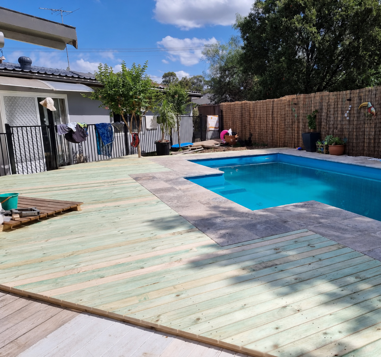 New timber decking laid around a swimming pool with stone coping