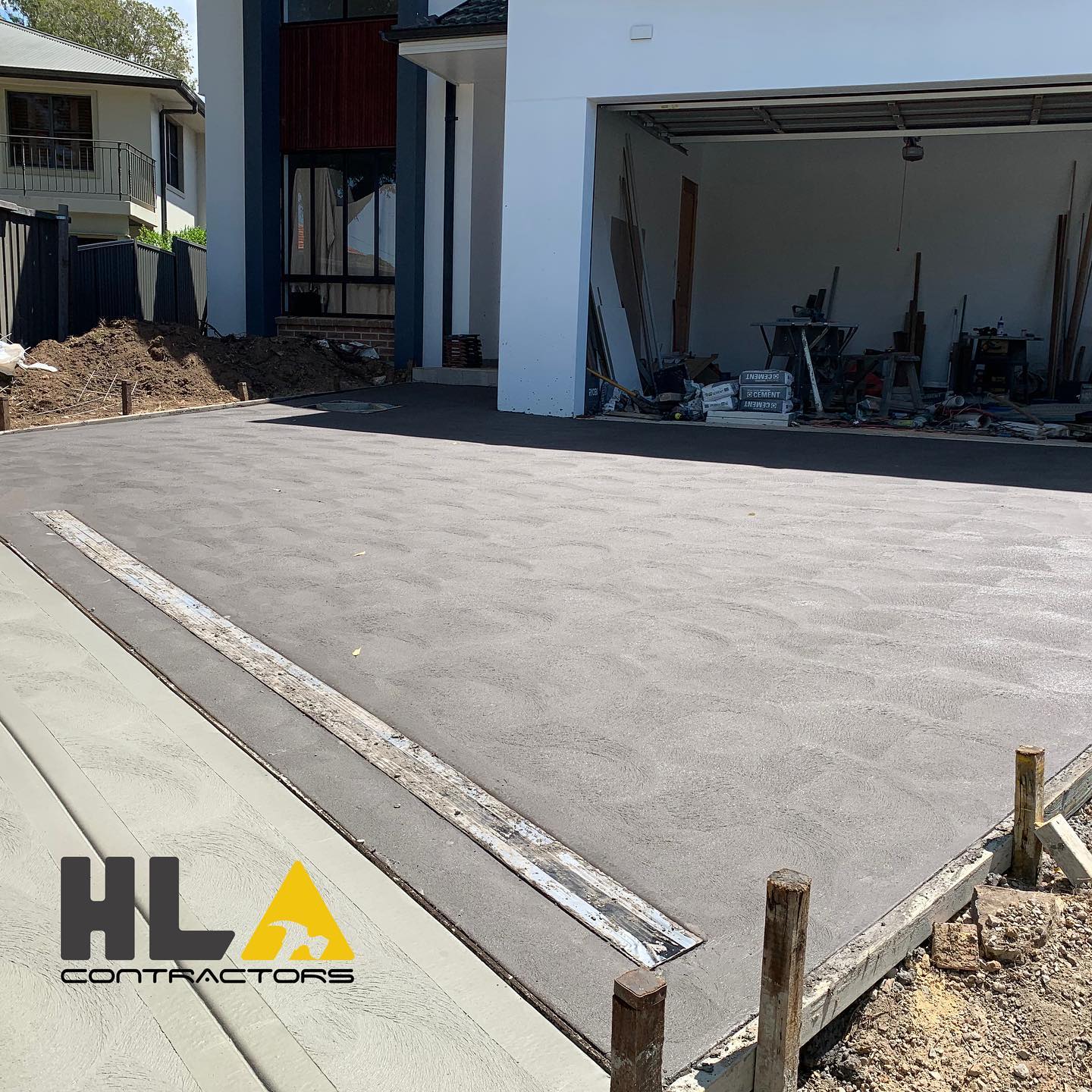 Large new concrete driveway with drainage grate and formwork at a residential site