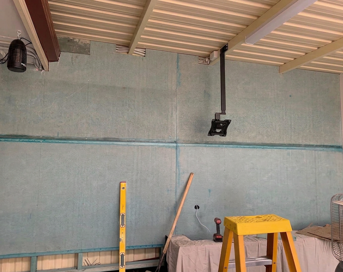 Interior fit-out with panelled walls, ceiling structure, and tools on site
