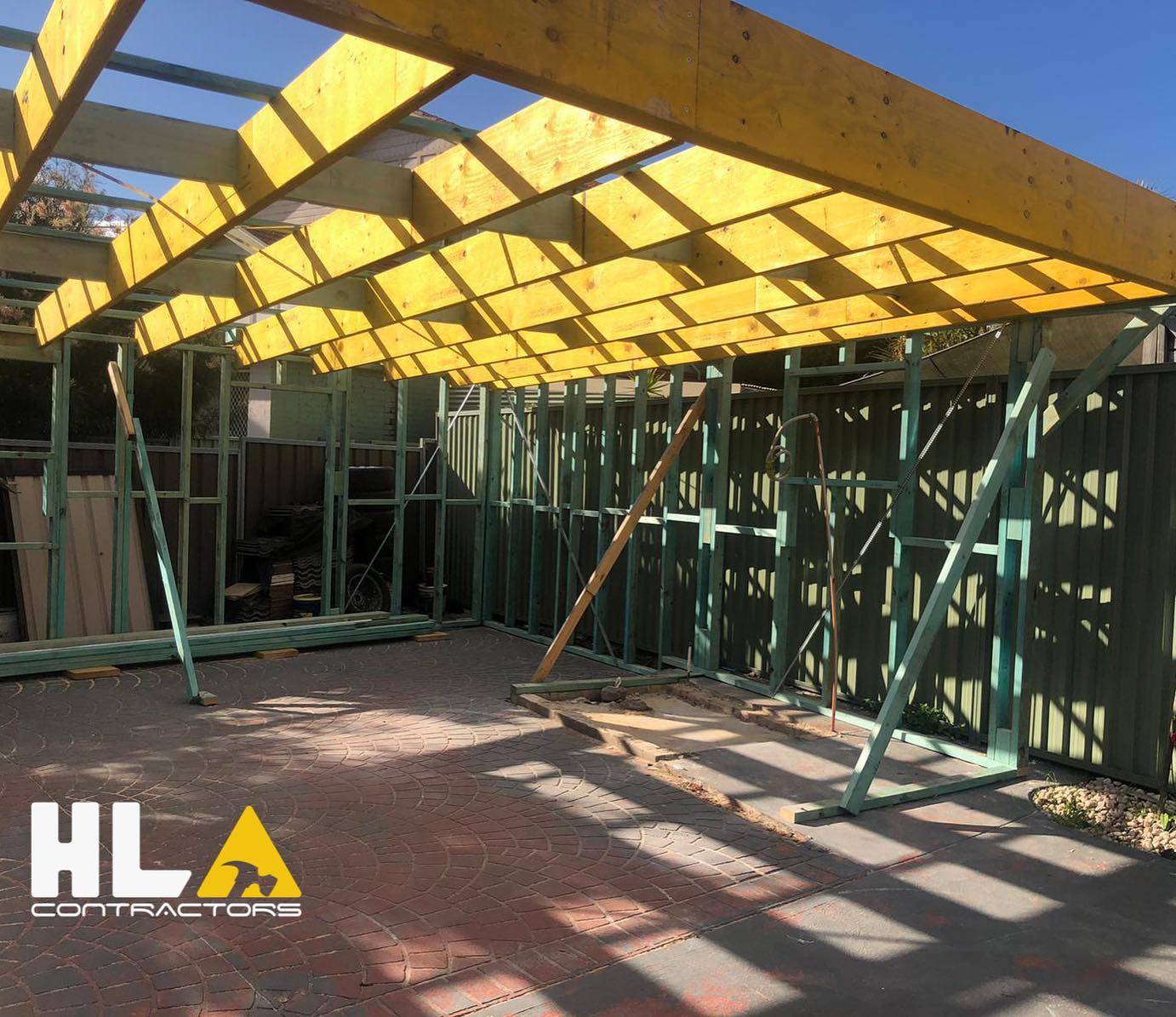 Outdoor timber wall and roof framing for a patio extension over paved brick