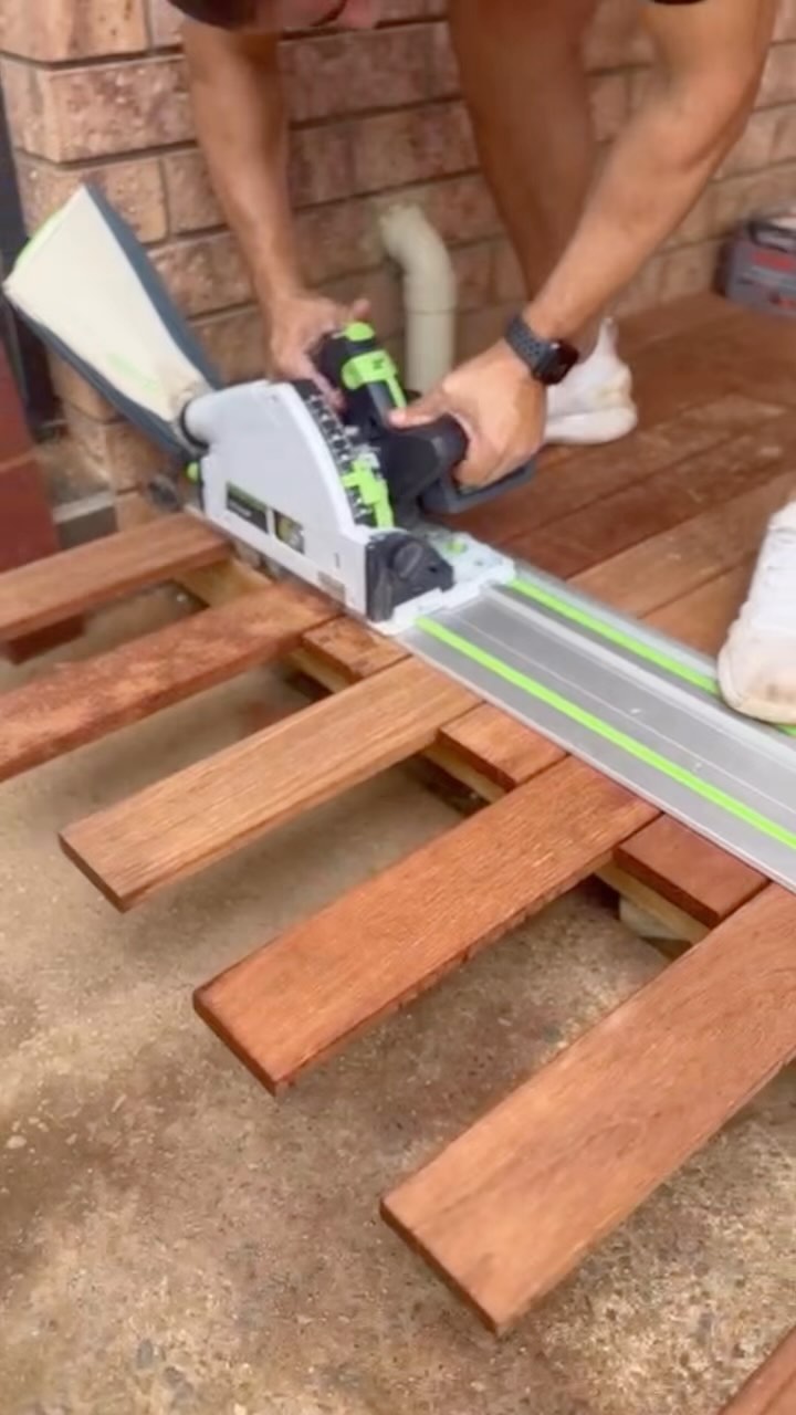 Worker using a track saw to trim timber decking boards to length