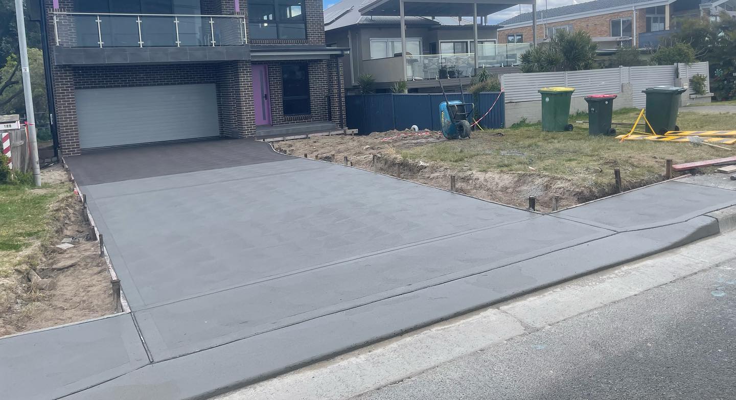 Fresh concrete driveway pour in front of a modern home